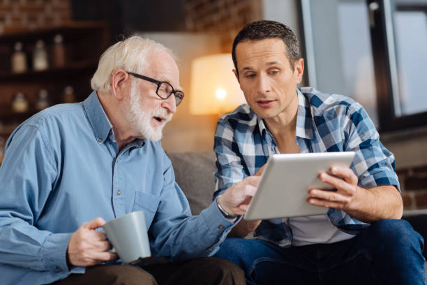 istock Caring son showing interesting article on tablet to his father 887442522