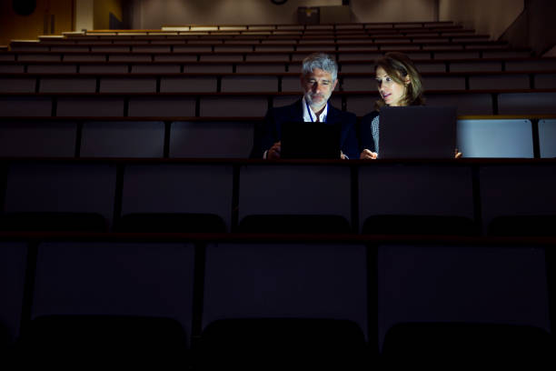 istock Couple Working Alone in a Seminar Room in the Dark 887447138