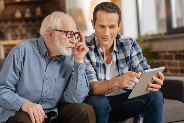 istock Young man demonstrating article on tablet to his father 887447414