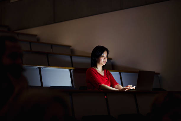 istock Woman Working Alone in a Darkened Seminar Room 887448214