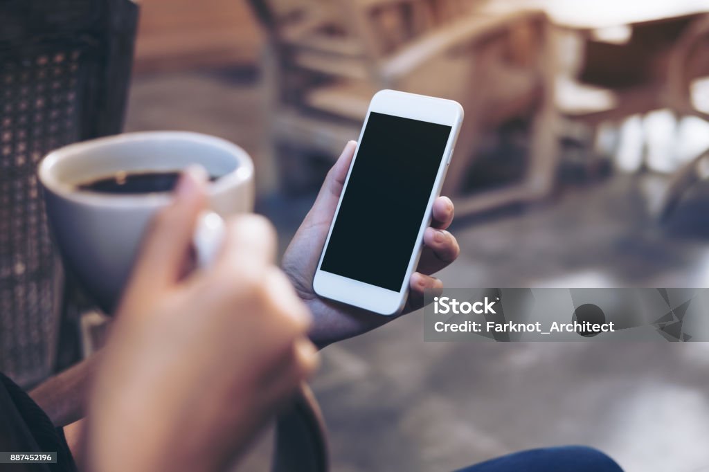 Image de maquette de femme mains tenue blanche portable avec un écran noir vide tout en buvant du café au café loft moderne - Photo de Café - Boisson libre de droits