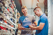 Two man deciding on new sports shoes in sports store