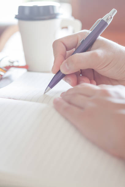 istock Close-Up Of Hand Writing With Pen On Paper 887461420