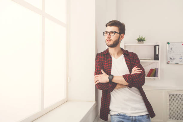 istock Confident young businessman at office near window 887465796