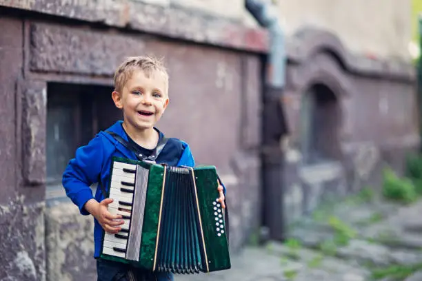 Photo of Cute little boy playing accordion