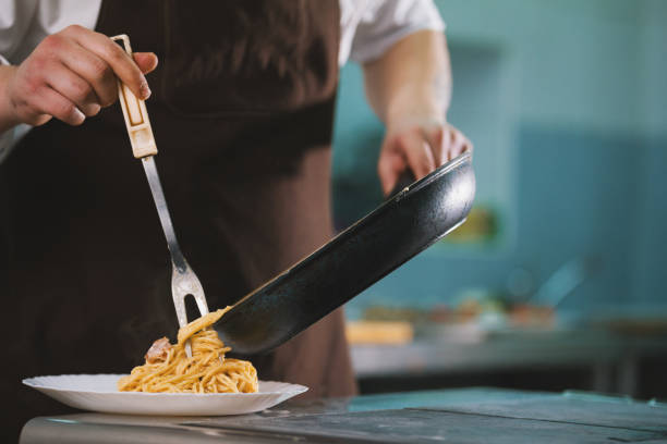 istock Chef serves spaghetti carbonara on the plate in restaurante 887471510