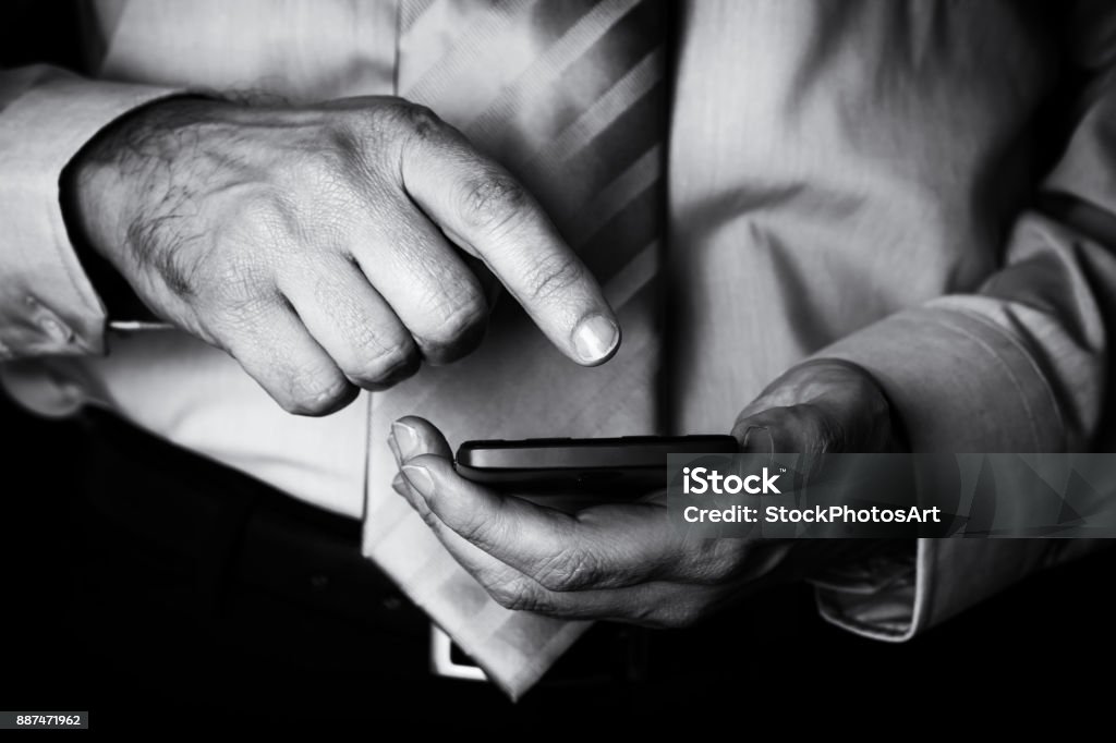 Uomo che tiene e tocca lo schermo o il display con il dito di un telefono cellulare, cellulare o smartphone. - Foto stock royalty-free di Bianco e nero