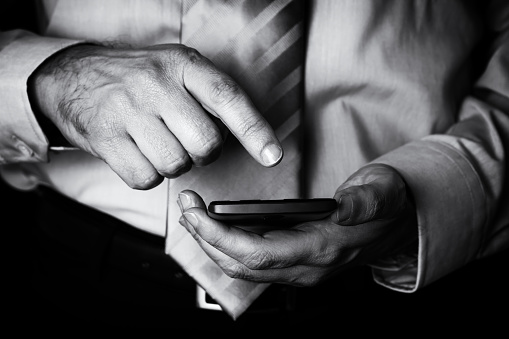 Man holding and touching screen or display with finger of a mobile phone, cell phone or smartphone. Male businessman typing a message or browsing the internet for apps on wireless digital device