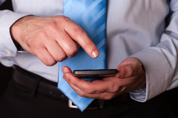 homem segurando e tocar a tela ou exibir com o dedo de um telefone móvel, telefone celular ou smartphone. - shirt and tie typing communication part of - fotografias e filmes do acervo