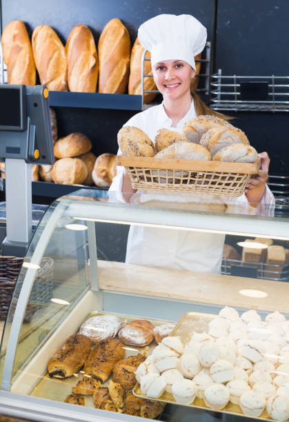 istock Female baker is offering fresh baguettes and buns 887477160