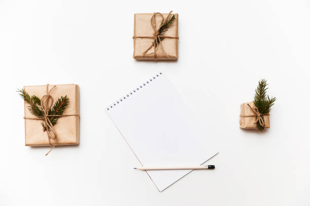 istock Empty notebook, pencil and gift boxes or presents packed in kraft paper isolated on white, top view 887478706