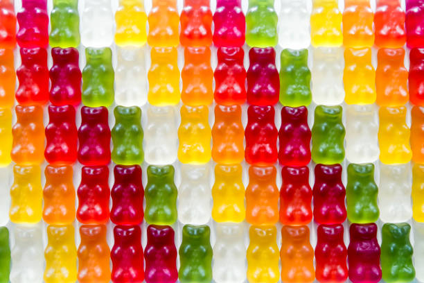Multi colored gummy bears candy in a row arrangement close-up studio shot Horizontal composition photography of gradient multi colored (red, green, yellow, orange, white etc...) colorful gummy bears candy in a row arrangement close-up studio shot on white background. Picture taken in close-up with selective focus. gummi bears photos stock pictures, royalty-free photos & images