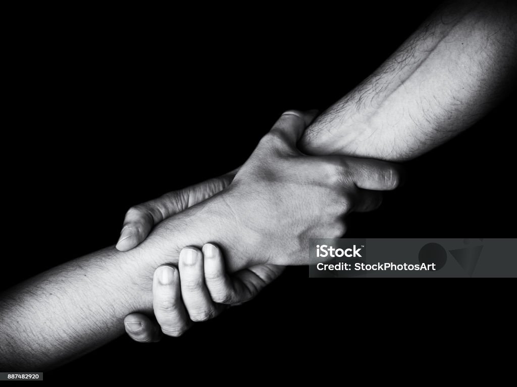 Man saving, rescuing and helping woman by holding or griping the forearm. Man saving, rescuing and helping woman by holding or griping the forearm. Male hand and arm pulling up female. Concept of rescue, love, friendship, support, teamwork, partnership, reaching, couple Hand Stock Photo