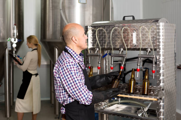 istock Man employee bottling beer in glass bottles 887489568