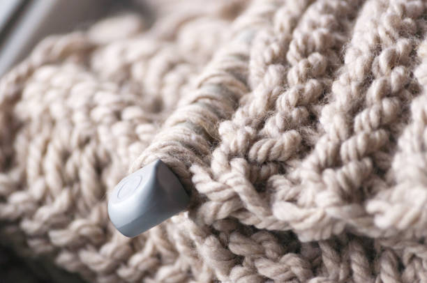 istock A knitted scarf with a thick thread on thick beige knitting needles. Close-up with blur. 887491038