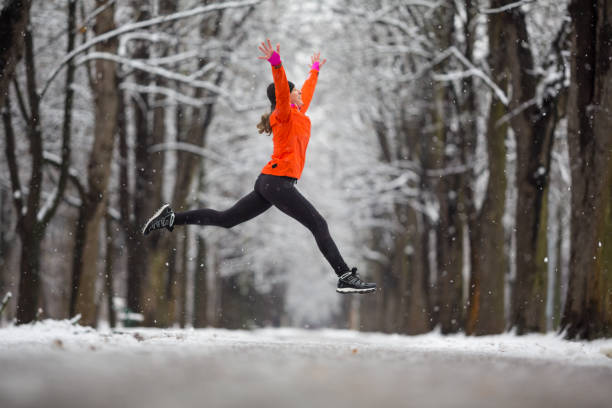 ジャンプ!-冬の喜びのためにジャンプ サイド ビュー女性 - healthy lifestyle women jumping happiness ストックフォトと画像