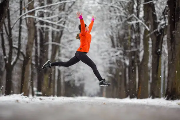 Photo of Jump! - side view woman jumping for joy in winter