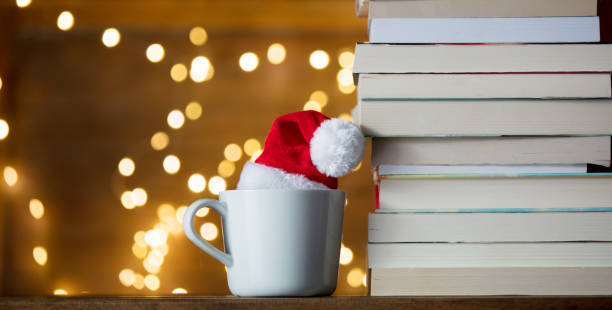 white cup with Christmas hat and books