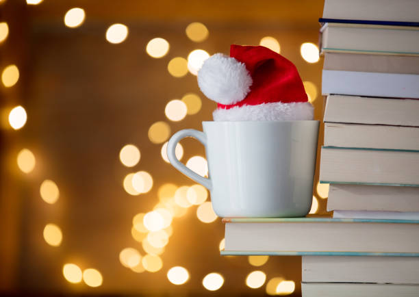 istock White cup and Christmas hat near books 887494830