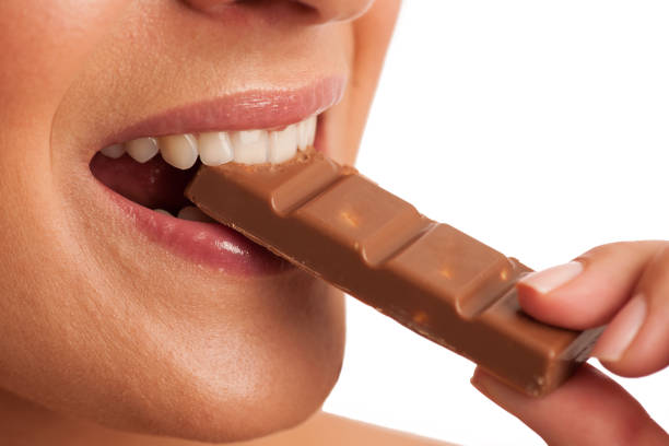 istock Beautiful young woman eats chocolate isolated over white background 887495038