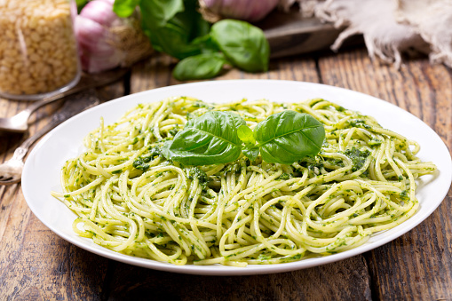 plate of pasta with pesto sauce on wooden table