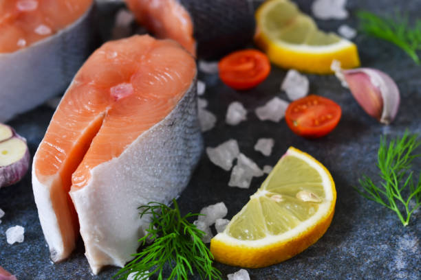 istock Fresh raw salmon steak with lemon and salt on black marble background 887533176