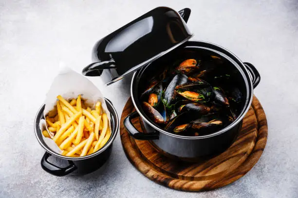Shellfish Mussels Clams in black cooking dish pan and French Fries
