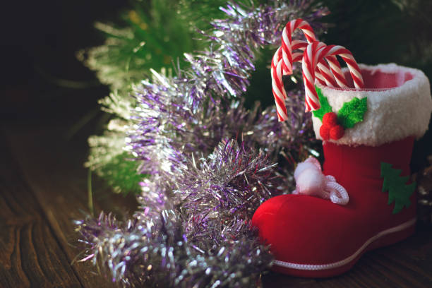 istock Christmas decoration - red boot with candy canes on dark wooden background. 887558484
