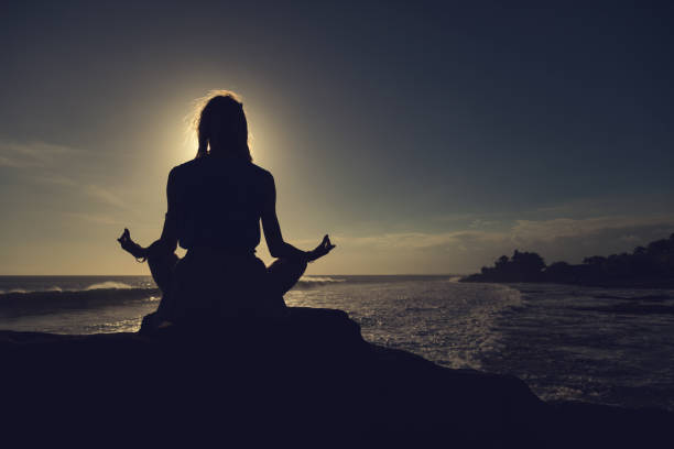 istock Young woman practicing yoga on the beach. 887564378