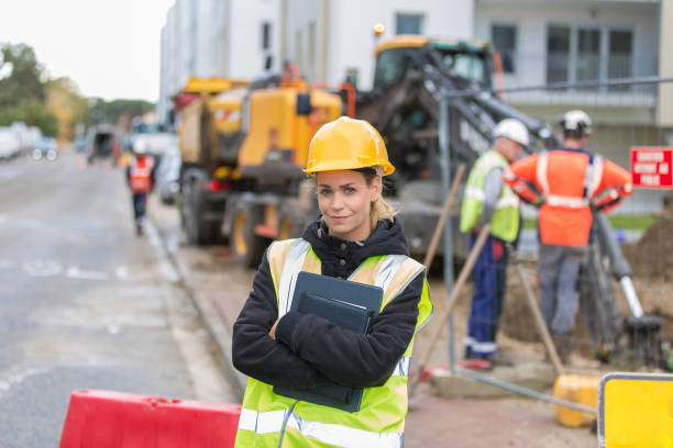 istock female construction worker managing team at building site 887588724