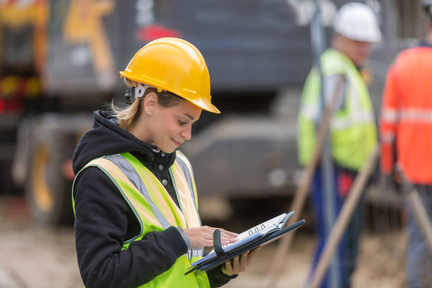 istock female builder in hardhat with tablet pac at construction with her team 887588754
