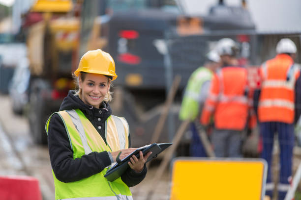 istock female builder in hardhat with tablet pac at construction with her team 887588762