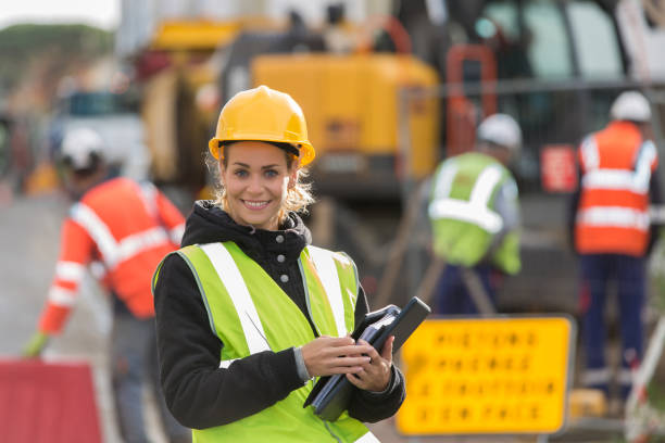 istock female construction worker working with her team and wearing hardhat 887588808