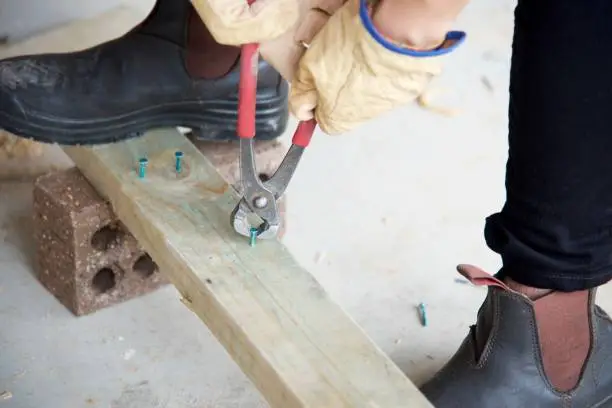 View of a male construction worker using a nail puller on timber