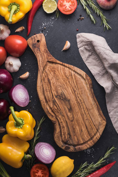 istock Top view of the rustic cutting board on the black kitchen table among fresh vegetables, herbs and spices. The concept of healthy and organic food. 887592316