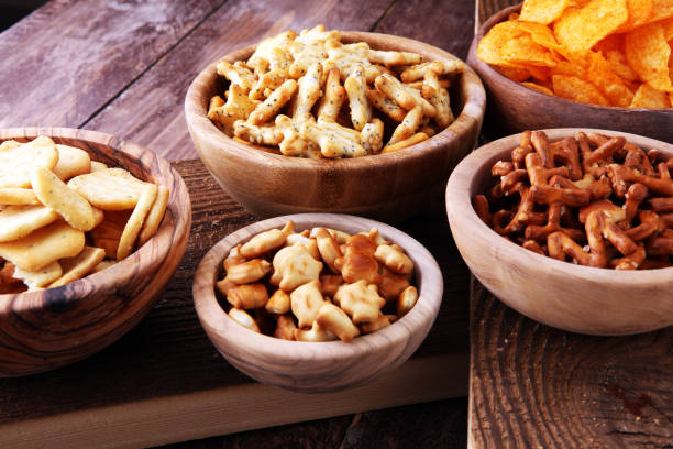istock Salty snacks. Pretzels, chips, crackers in wooden bowls 887599954