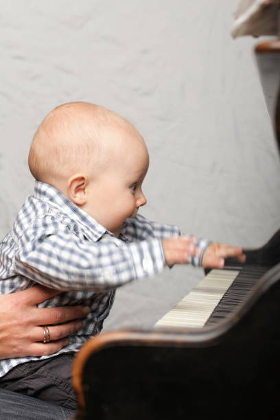 istock beautiful little baby boy plays piano 887606576