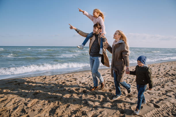 istock family walking on seashore in autumn 887616118