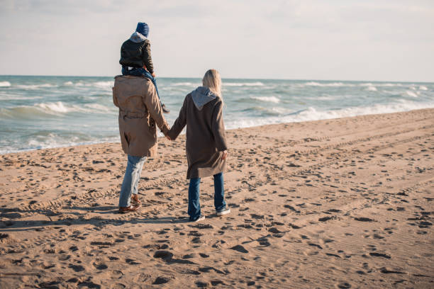 istock family walking on seashore in autumn 887620312
