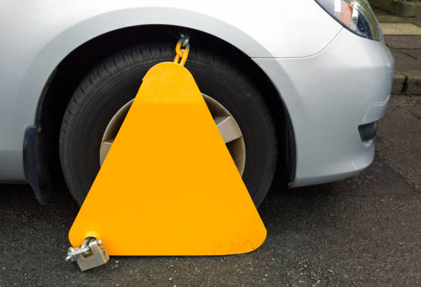 Wheel clamp locking car for parking infringement A wheel clamp immobilising an illegally  parked car. car boot stock pictures, royalty-free photos & images