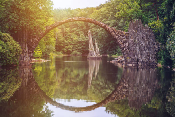 ponte rakotz (rakotzbrucke) noto anche come ponte del diavolo a kromlau, germania. il riflesso del ponte nell'acqua crea un cerchio completo. - spring forest scenics reflection foto e immagini stock