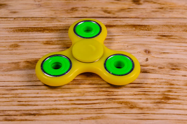 istock Yellow fidget spinner on wooden desk 887627138