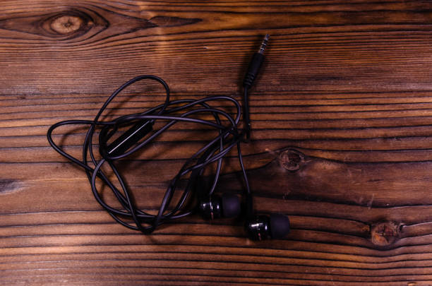 istock Black earphones on wooden table. Top view 887627146