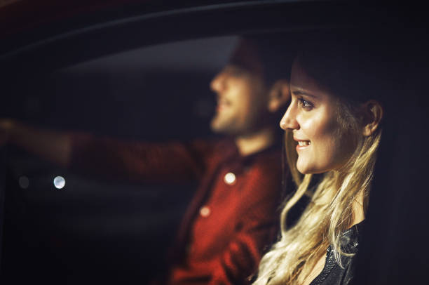 On our way to somewhere special Shot of a young couple traveling in a car together at night couple driving at night stock pictures, royalty-free photos & images