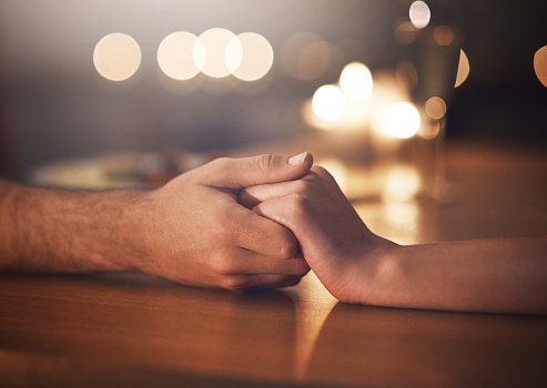 Cropped shot of a couple holding hands against a night time background