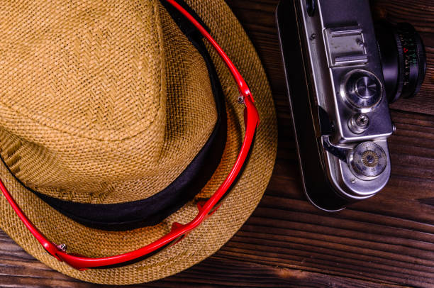 istock Old rangefinder camera, sunglasses and hat on a wooden table. Top view 887632680