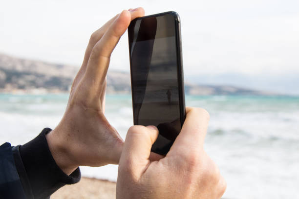 istock Man photographing sea with his phone 887632770