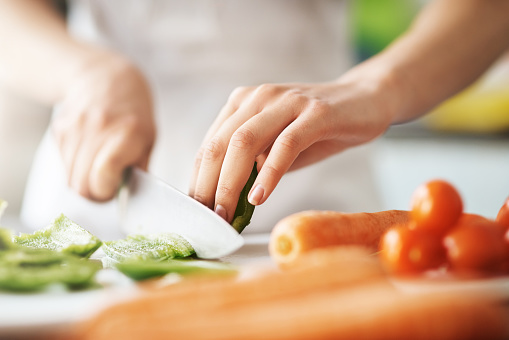 Closeup shot of a young woman chopping vegetables in the kitchen