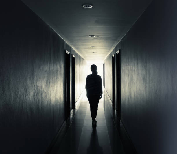 le donne camminano da sole al buio. luce alla fine del concetto di tunnel - muro di morte foto e immagini stock