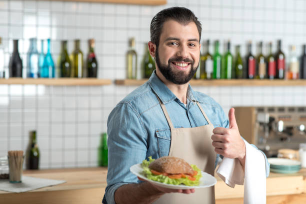 istock Enthusiastic bearded waiter feeling good while holding a plate with food 887677306